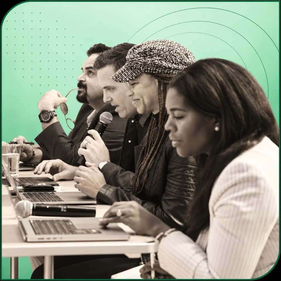 A panel of judges with laptops and microphones listening to a founder pitch